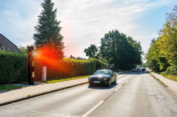 Ein zu schnell fahrendes Auto wird geblitzt.