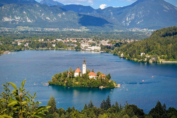 Auf einer kleinen Insel in einem Fluss stehen mehrere Häuser und ein Kirchturm.