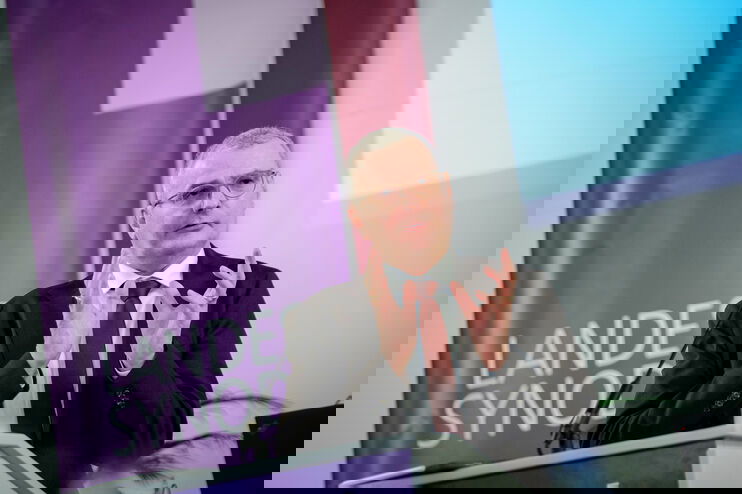 Eine männlich lesbare Person an einem Rednerpult