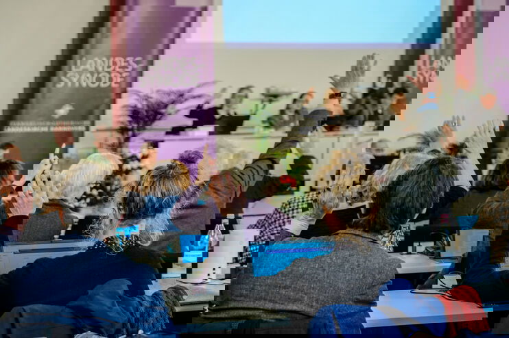 Menschen sitzen und heben die Hand zurAbstimmung