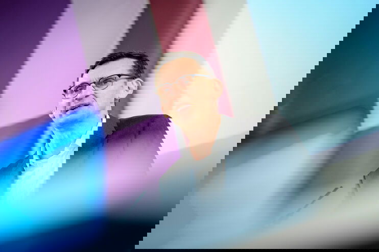 Eine männlich gelesene Person mit Brille und kurzen Haaren am Podium.