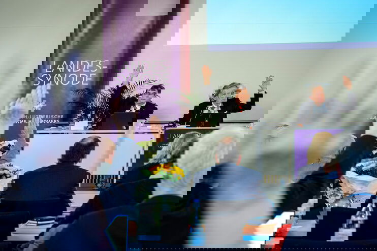 Personen haben die Hände erhoben und stimmen ab