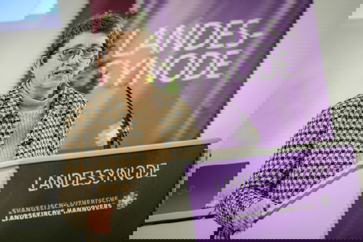 Eine weiblich lesbare PErson steht am Rednerpult und spricht