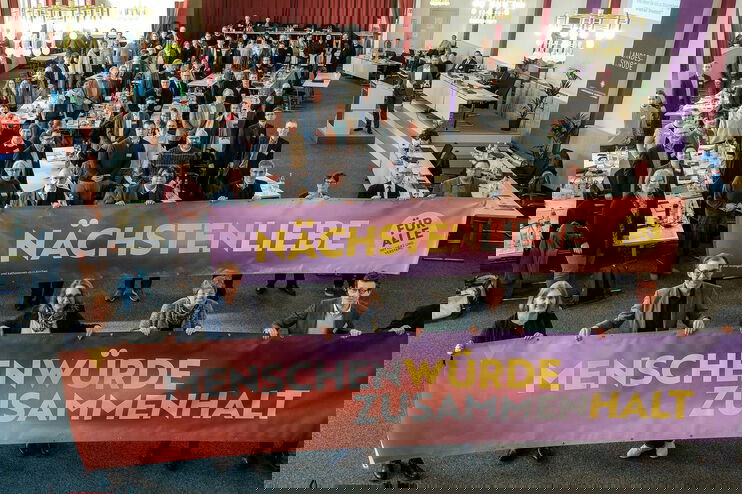 Viele Personen halten Banner mit der Aufschrift Nächstenliebe, Menschenwürde, Zusammmenhalt