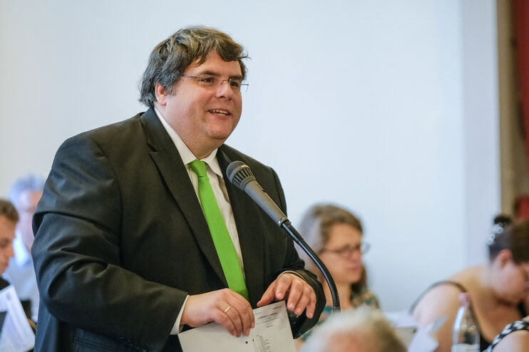 Eine männlich lesbare Person an einem Mikrofon