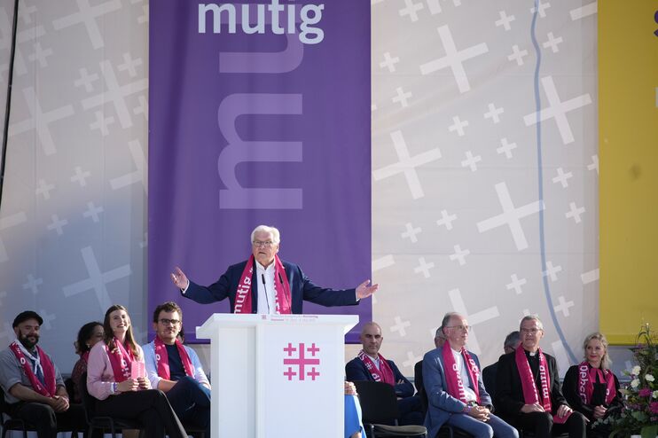 ein Mann steht hinter einem Altar, hinter ihm sitzen mehrere Personen