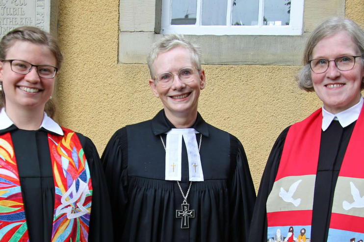 Auf dem Bild sind Laura Wolkenhauer, Regionalbischöfin Petra Bahr und Superintendentin Antje Marklein in Amtskleidung am Tag der Ordination zu sehen.