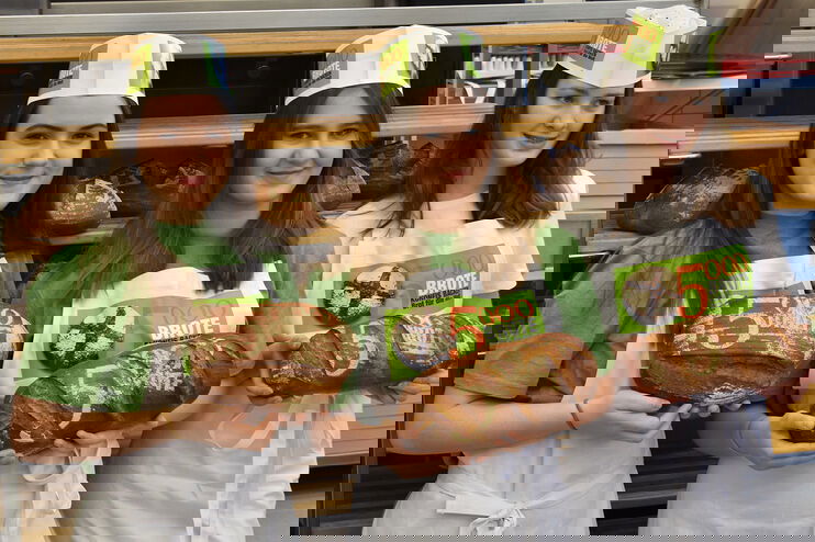 Drei Mädchen stehen in einer Backstube und halten Brot in den Händen