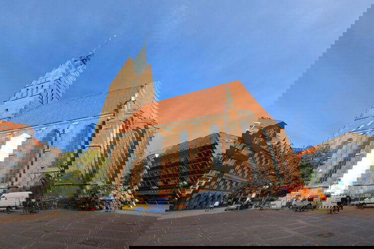 Eine große Kirche unter blauem Himmel, bei der ein Fenster abgeklebt ist.