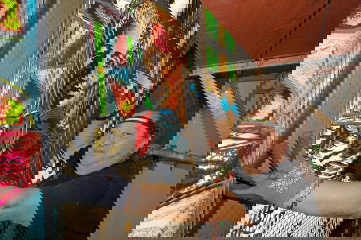 Ein Handwerker mit Kappe und Handschuhen prüft den Sitz eines Kirchenfensters.