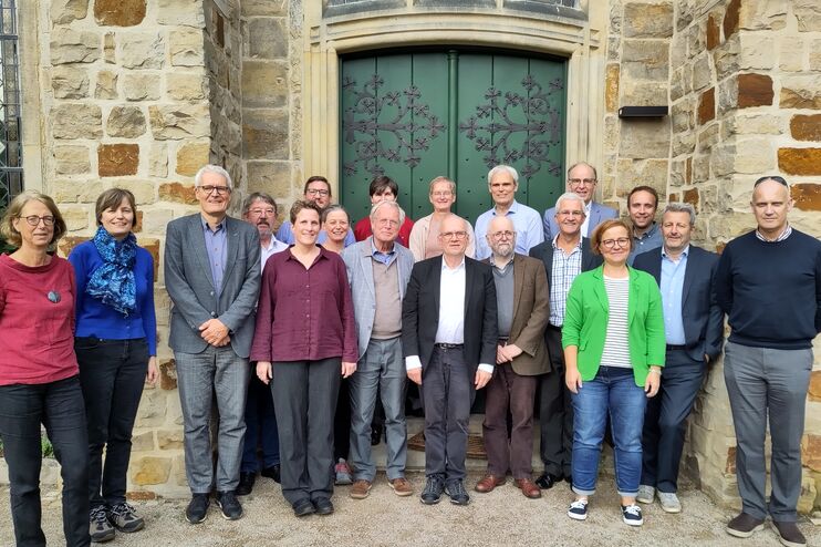 Eine Gruppe von Frauen und Männern stehen für ein Gruppenbild vor der Tür einer Kirche.