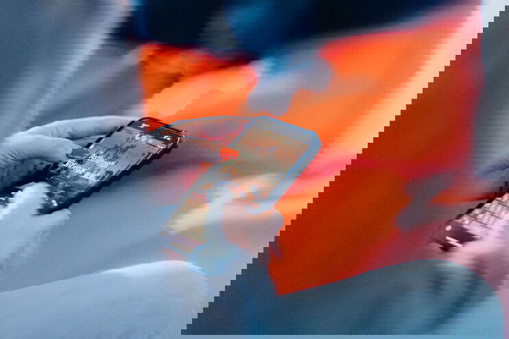 Blick an einem Arm vorbei auf ein Smartphone, auf dem steht: "Ästhetisch können wir auch"