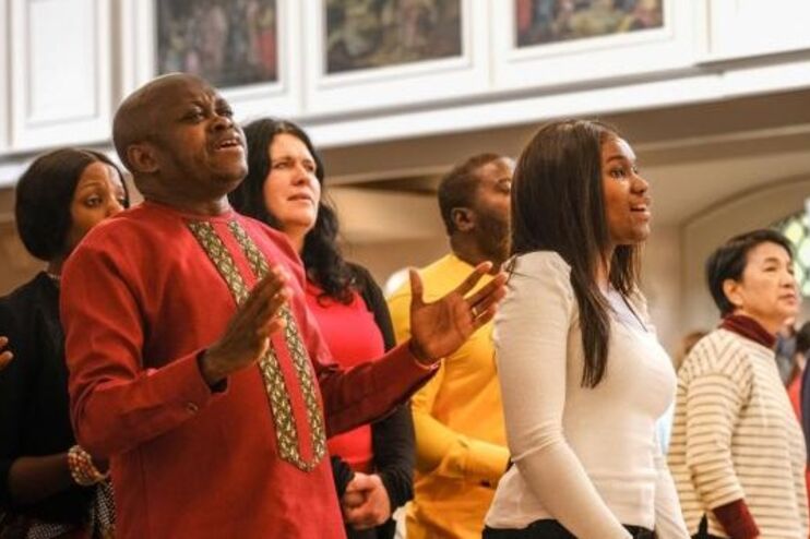 Menschen schwarzer Hautfarbe singen nach vorne blickend. 