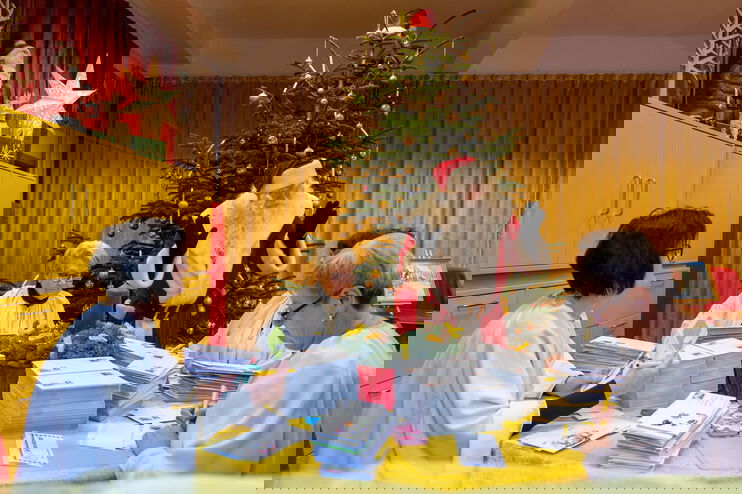 Mehrere Frauen sortieren Post, der Weihnachtsmann schaut zu.