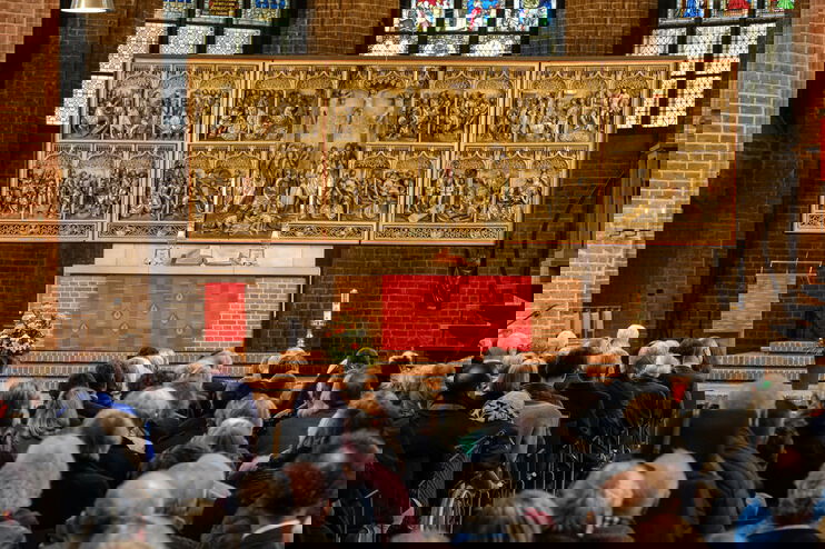 Ein Pastor im Talar steht an einem Altar in der Kirche und predigt.