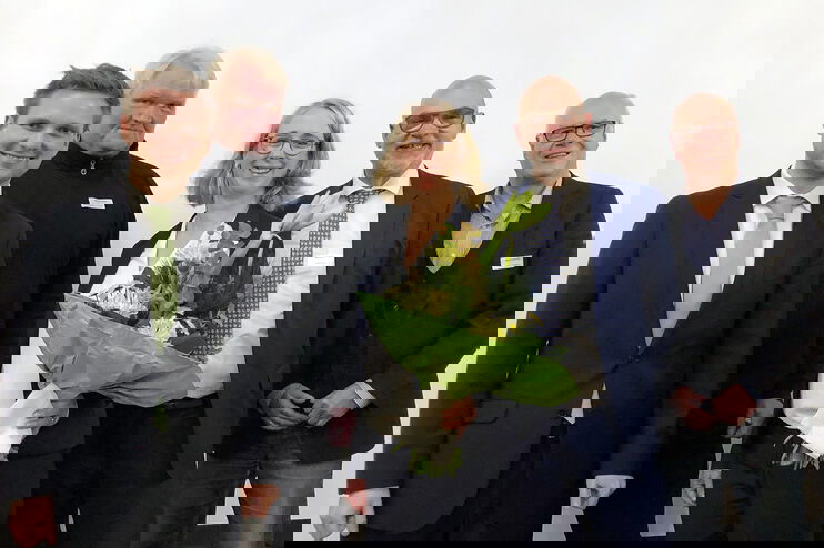 Gruppenbild mit vier Männern und einer Frau, die einen Blumenstrauß hält.