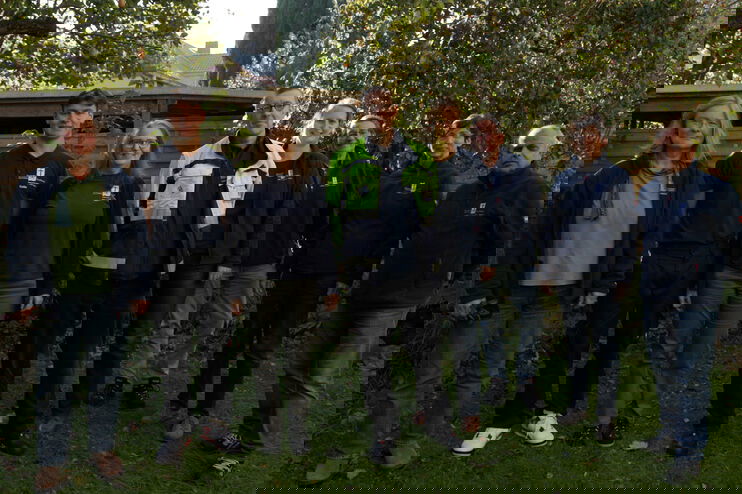 Mehrere Menschen stehen in einer Reihe im Grünen.