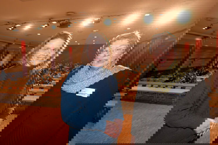 Eine junge und eine ältere Frau stehen in einem großen Saal.