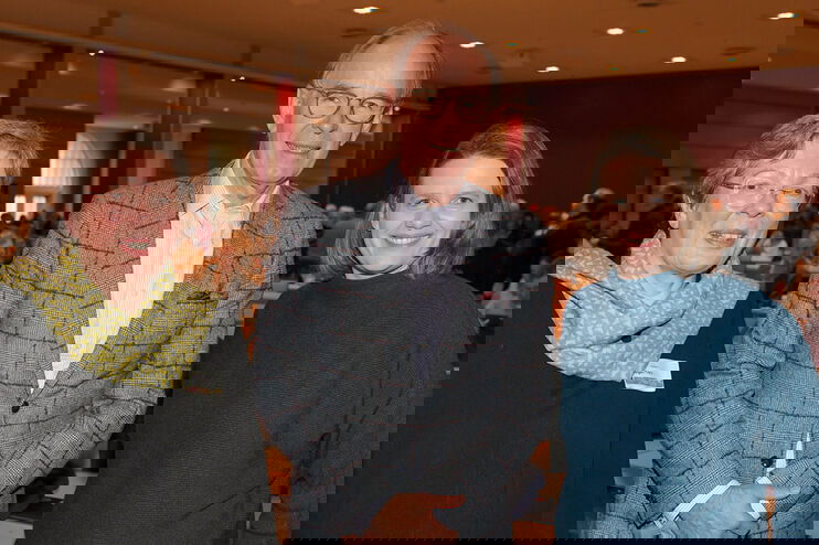 drei Menschen lächeln freundlich in eine Kamera