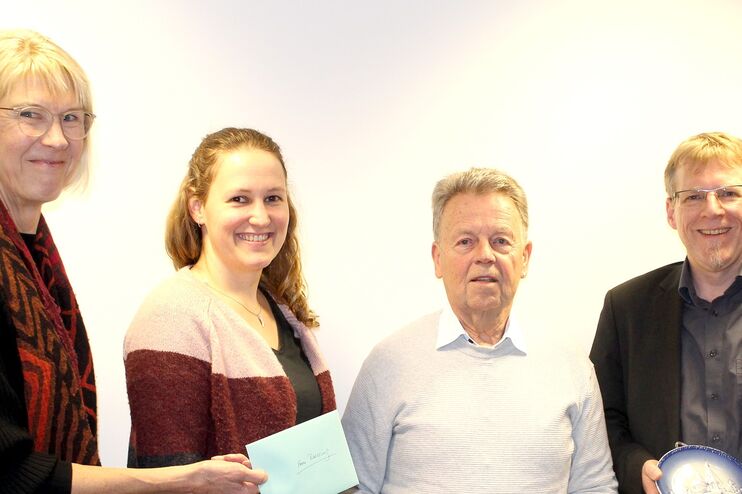 Zwei Frauen und zwei Männer stehen nebeneinander. Eine Frau hält einen Zettel in der Hand, alle lächeln.