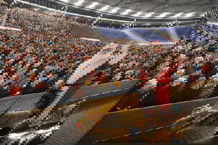 Ein Weihnachtsmann winkt vor einer Stadiontribüne voller Menschen.