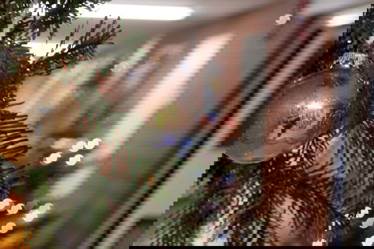 ein Weihnachtsschmuck mit Tannengrün und Christaumkugeln. Im Hintergrund ist ein Gefängnistrakt.