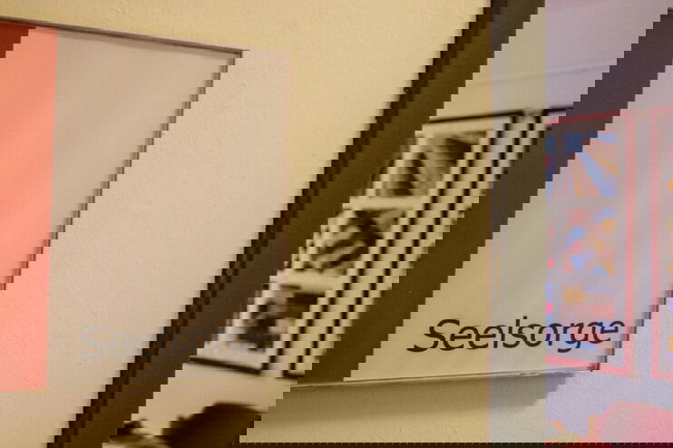 Ein Türschild mit dem Wort Seelsorge darauf. Im Hintergrund stehen Stuehle und ein Besprechungstisch.