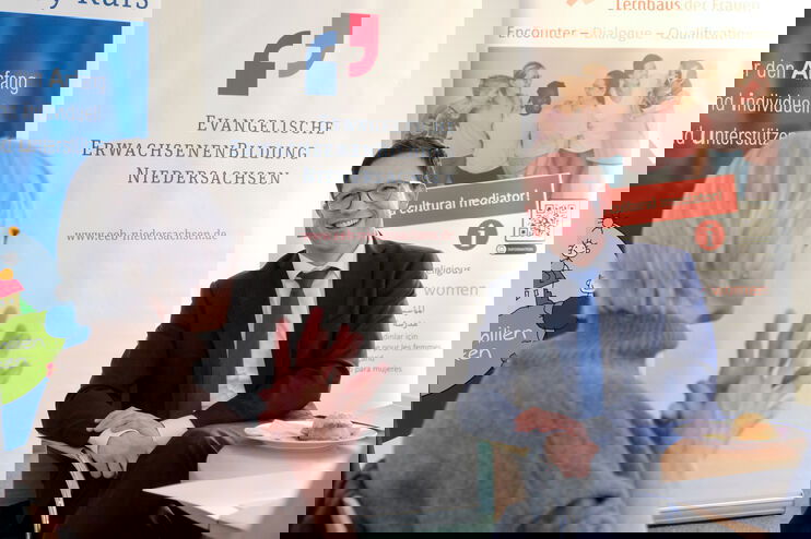 Eine Frau mit grauen Haaren im Gespräch mit einem jungen Mann im Anzug.