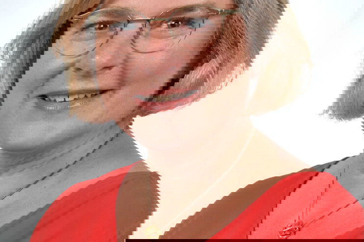 Portraitfoto einer als Frau lesbaren Person mit schulterlangen Haaren.