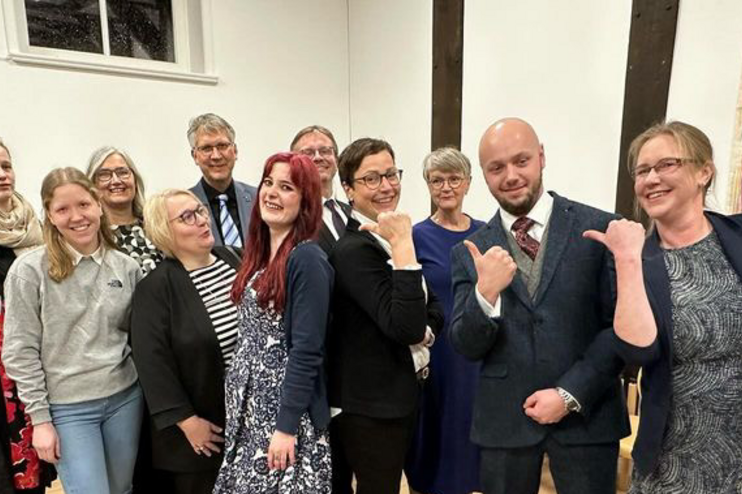 Ein Gruppenfoto mit Menschen in einem Raum mit hellen Wänden. 