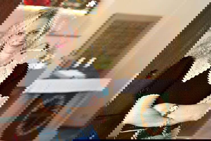 Eine als Frau lesbare Person lehnt an einer Säule in einer Kirche.