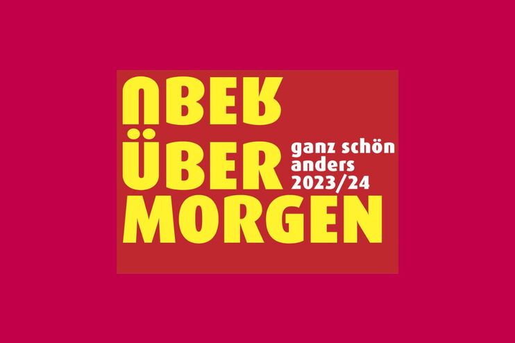 Auf rotem Grund steht in gelb: Überübermorgen, wobei das erste Wort "Über" auf dem Kopf steht und sich die Ü-Punkte mit den zweiten Wort 2über" teilt.