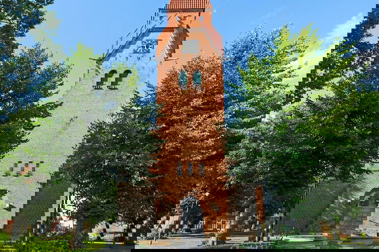 Ein Kirchturm, umgeben von Bäumen.