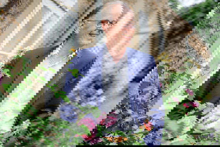 Eine männlich gelesene Person in einem Garten mit Rosen