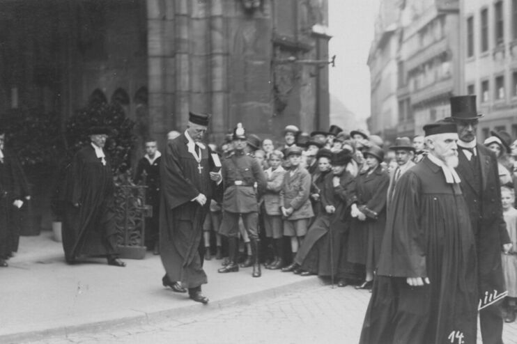 Eine historische Schwarzweiß-Aufnahme: Mehrere Männer ziehen aus einer Kirche aus.