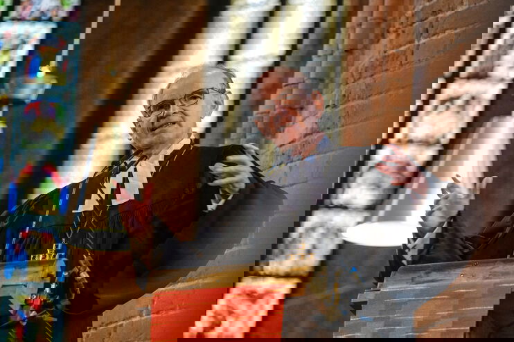 Eine als Mann lesbare Person steht auf der Kanzel und predigt.