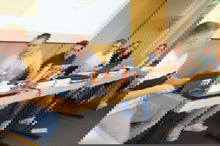 Mehrere junge Menschen sitzen an einem Tisch und diskutieren.