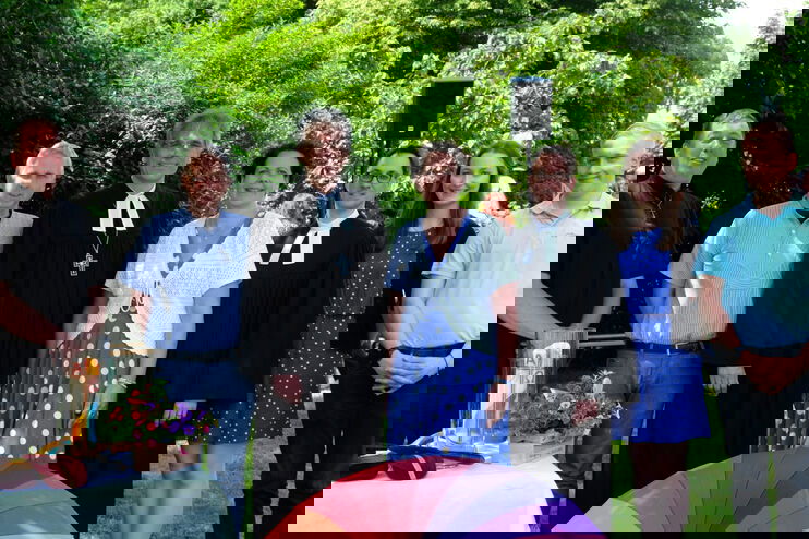 Sieben Personen, fünf männlich gelesene und zwei weiblich gelesene stehen zusammen, zwei tragen Talar.