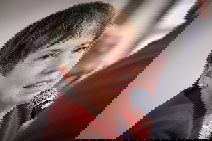 Eine als Frau lesbare Person spricht in ein Mikrofon.