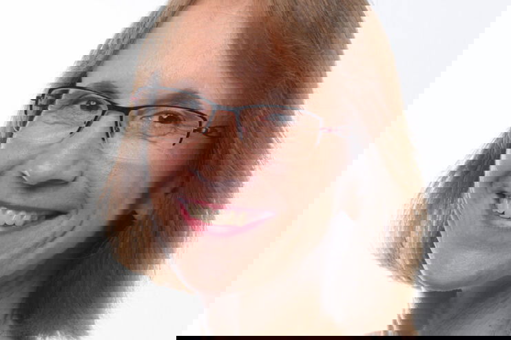 Eine als Frau lesbare Person mit Brille und schultelangen Haaren