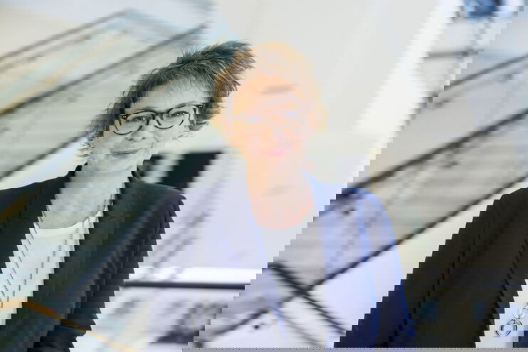 Eine als Frau lesbare Person mit Brille und kurzen Haaren