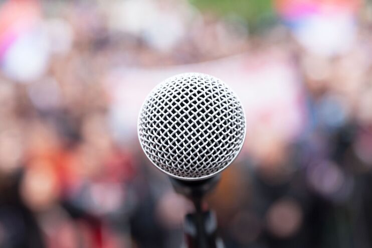 ein mikrofon. Im Hintergrund unscharf eine Menschenmenge
