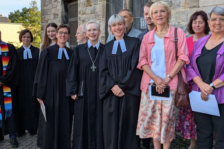 Eine Gruppe von Menschen vor einer Kirche in Talaren.
