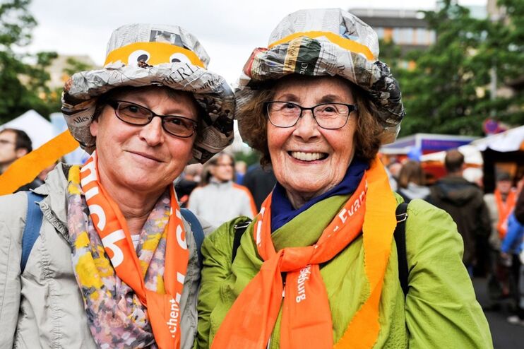 Zwei lächelnde Frauen stehen zwischen Ständen