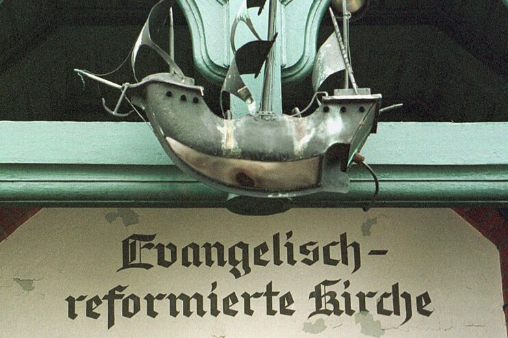 Der Eingang einer Kirche. Über der Tür ein Schiff aus Stahl.