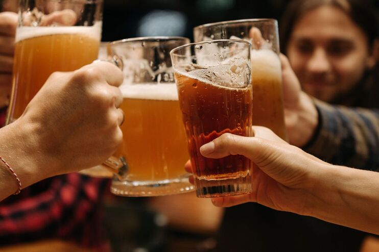 Menschen stoßen mit Getränken miteinander an.