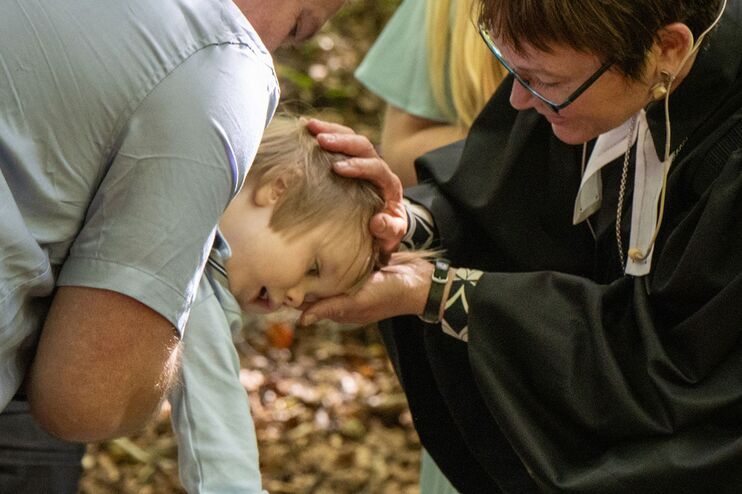 Ein Kind wird von einer Pastorin getauft.
