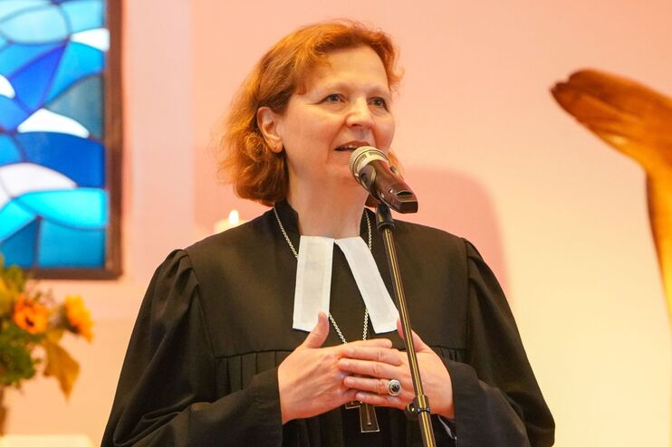 Eine Frau im Talar steht vor einem blauem Buntglasfenster und einer goldenen Skulptur: Regionalbischöfin Sabine Schiermeyer