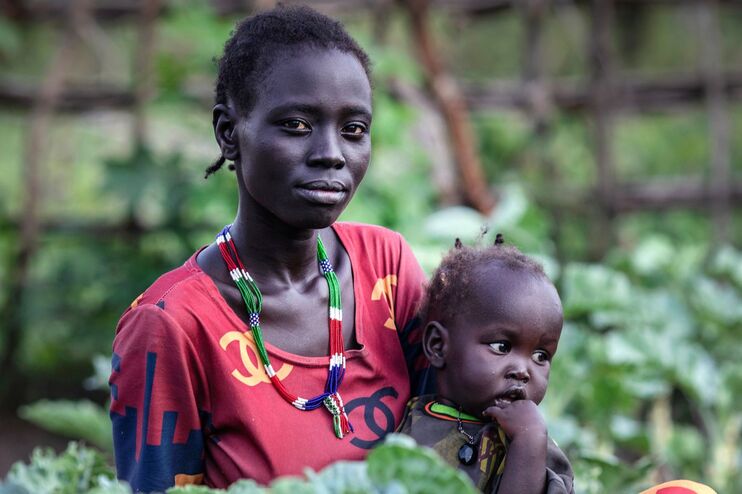 Eine farbige Frau hält ein Kind im Arm.