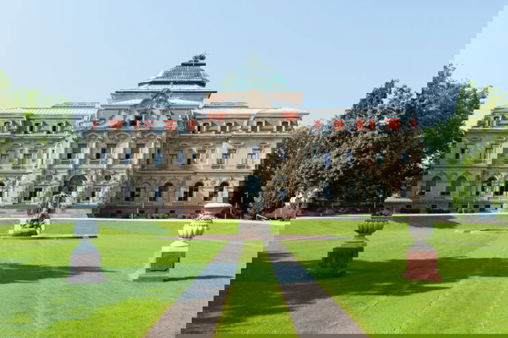 Ein altes herrschaftliches Gebäude mit einer großen Wiese davor.